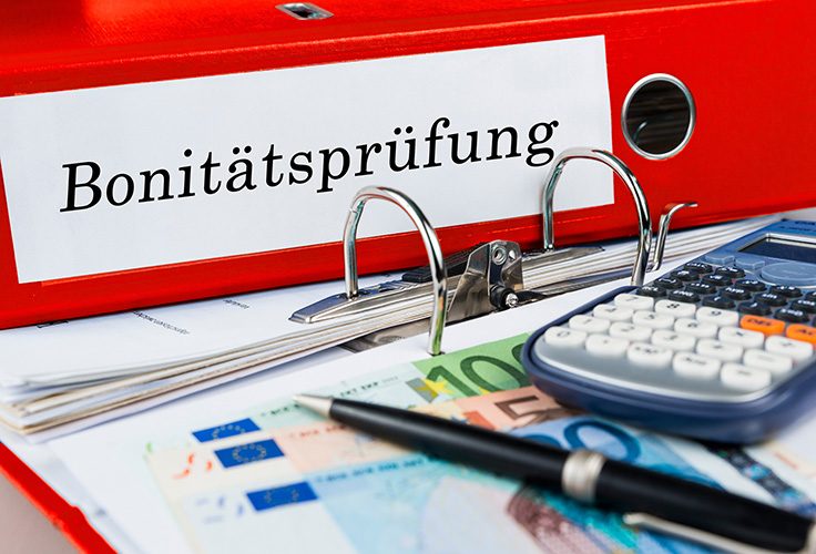 Aktenordner mit Aufschrift Bonitätsprüfung und Taschenrechner
