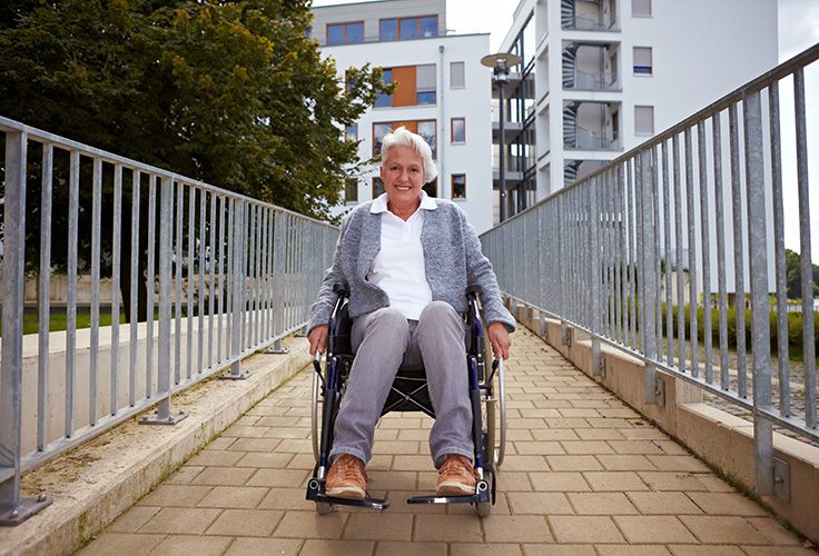 Frau im Rollstuhl lächelt in die Kamera