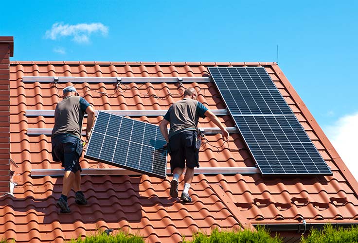 Auf einem Dach werden Photovoltaikanlagen montiert